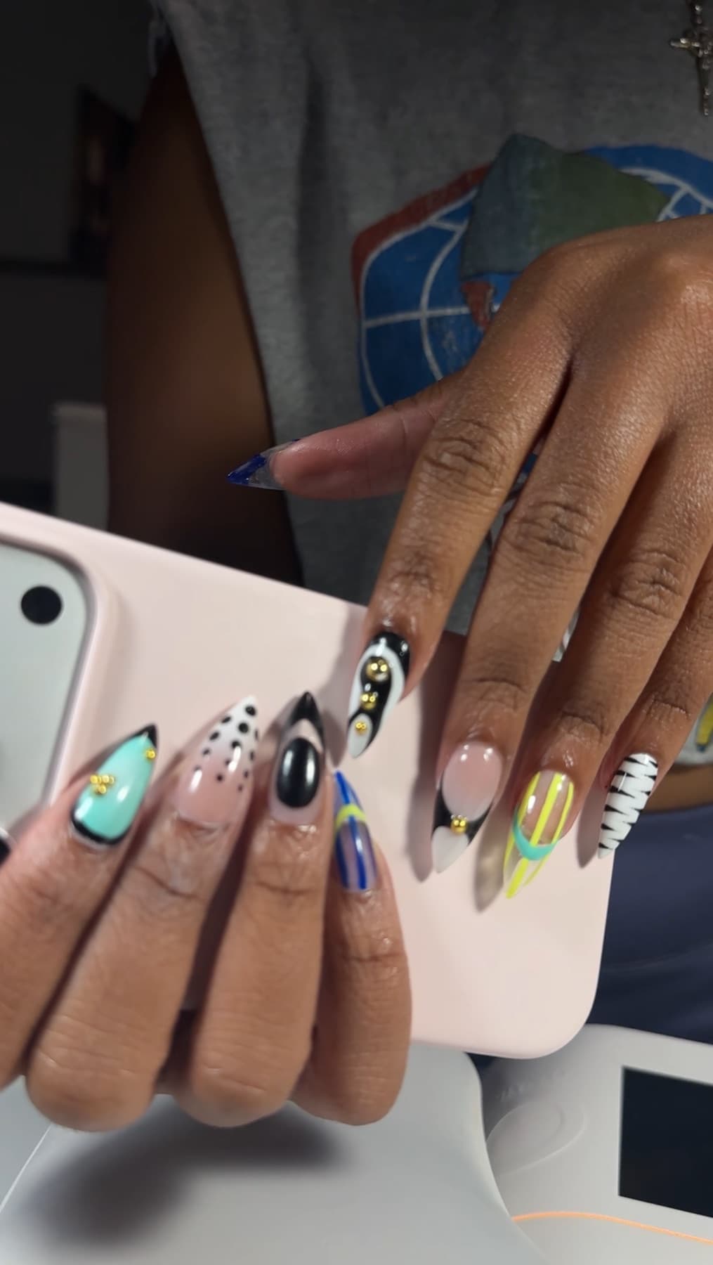 A display of finished nail art sets in black, white, mint and cobalt with gold stud detail